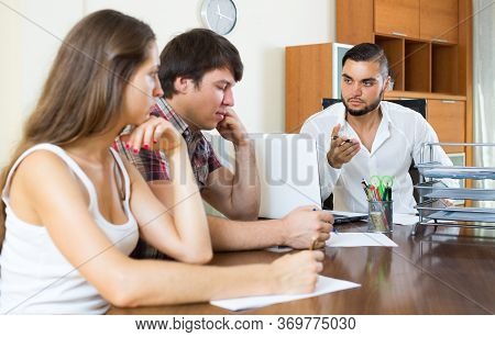 Bank Employee In The Office Trying Hard To Make Couple Pay Back A Loan.