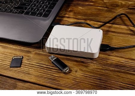 External Hdd Connected To Laptop Computer, Sd Memory Card And Usb Flash Drive On A Wooden Desk. Conc