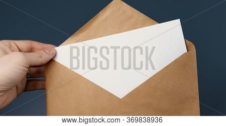 Cropped View Of Man Holding Craft Envelope With Blank White Card On Blue Background