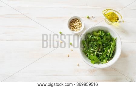 Fresh Vegetable Salad  With Greens, Cocumber Green Peas And Pine Nuts On  White Wooden Background. F