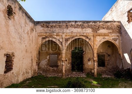 One Of Many Yards In An Abandoned House. Arcade With Arcs On A Columns.  Grass And Growing In The Ru