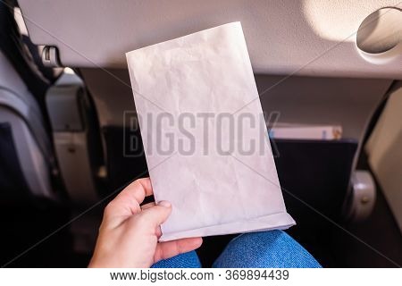 Air Sickness Paper Bag In The Hand Of Nauseous Passenger During Flight In The Airplane.