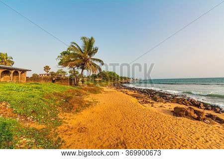 Monrovia, Liberia - April 23, 2019: Beach With Red Sand And Black Rocks With A Blue Sky In Congo Tow