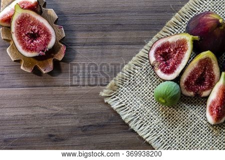 Figs, green leaves on rustic wooden background
