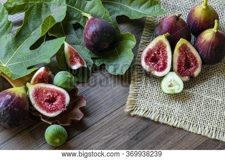 Figs, green leaves on rustic wooden background