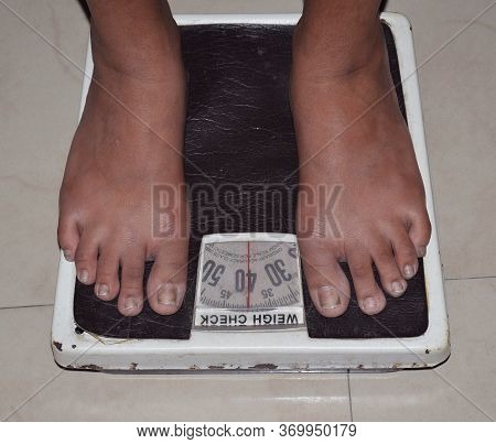 A Women Standing On Weighing Machine Or High Angle View Of Woman's Legs On Weighing Scale