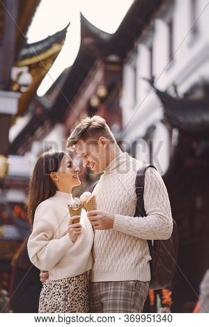 Newlywed Couple Eating Ice Cream From A Cone On A Street In Shanghai Near Yuyuan China.