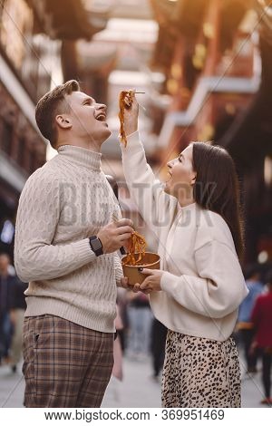 Newlywed Couple Eating Noodles With Chopsticks In Shanghai Outside A Food Market