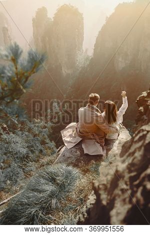 Newly Enageged Couple Hugging And Holding Hands As They Are Sitting On A Rock At Zhangjiajie Nationa