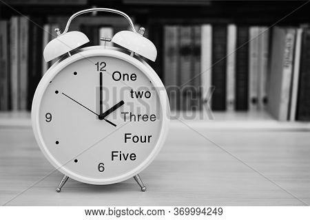 The Table Clock Alarm Clock In The Foreground Is Arranged Closeup Against The Blurred Background Of 