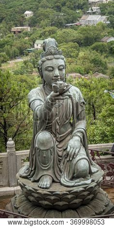 Buddhist Deva Statue Offering A Flower To The Tian Tan Big Buddha  Statue On Lantau Island, Hong Kon