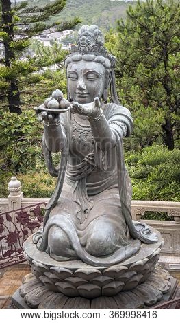 Buddhist Deva Statue Offering Fruit To The Tian Tan Big Buddha  Statue On Lantau Island, Hong Kong