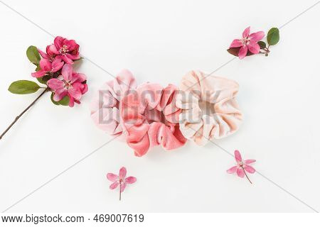 Three Trendy Pink Velvet Scrunchies And Fresh Spring Red Flowers On Whitel Background. Flat Lay, Top