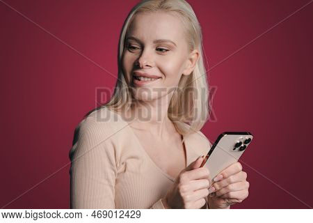 Beautiful Happy Woman Texting On Her Mobile Phone Isolated On Crimson Background. Technology, Connec