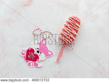 A Valentines Day Cakesicle Tied To A Card With A Ribbon.