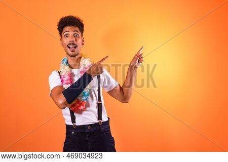 Portrait Of Black Man With Carnival Props Poiting,  Isolated On Orange Background