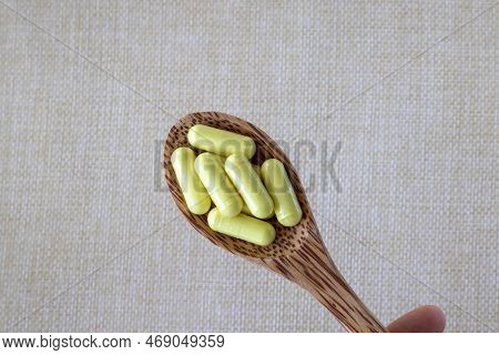 Yellow Quercetin Capsules In A Wooden Spoon On A Beige Background. Dietary Supplement, Vitamin Or Ta