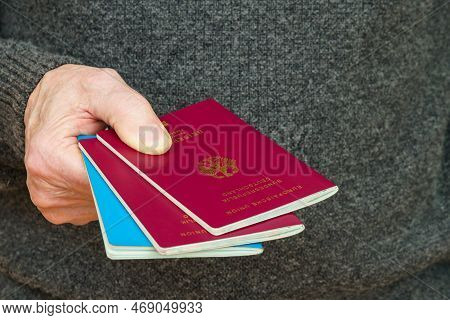 Male Hand Holds Out Two German Passports. Close Up.