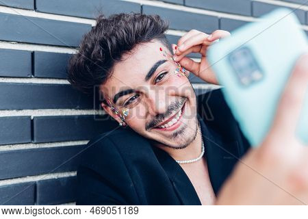Cheerful Young Gay Man With Colorful Stickers On Face Taking Self Portrait On Mobile Phone Against W