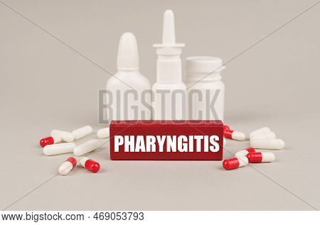 Medical Concept. On A Gray Surface Are Pills, White Jars And A Red Wooden Block With The Inscription