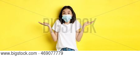 Covid-19, Quarantine And Social Distancing Concept. Clueless Asian Woman In Medical Mask Shrugging S