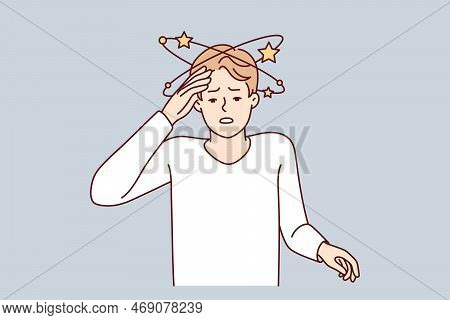 Suffering Man Experiencing Pain In Head After Severe Injury Puts Hand On Forehead. Guy Suffers From 
