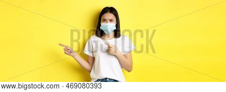 Covid-19, Pandemic And Social Distancing Concept. Disappointed Asian Girl In Medical Mask, Frowning 
