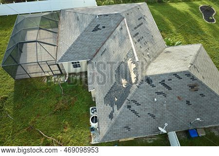 Wind Damaged House Roof With Missing Asphalt Shingles After Hurricane Ian In Florida. Repair Of Home