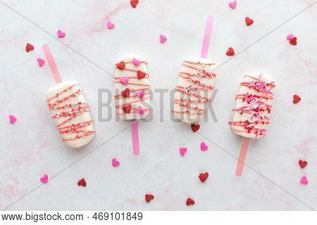 Valentines Day Cakesicles With Sprinkles On A Pink Marble Surface.