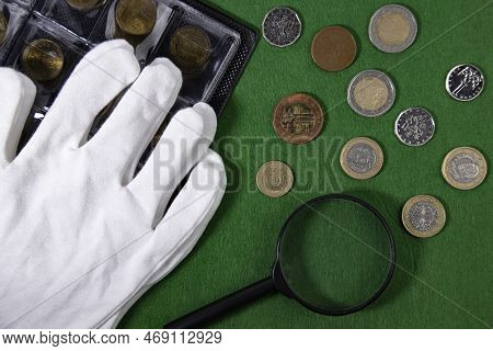 Coins On A Green Cloth, White Gloves And A Magnifying Glass, Top View.