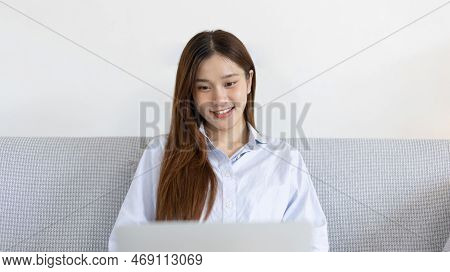 Woman using laptop to work or do homework at home with smiling face in her living room, Creating hap