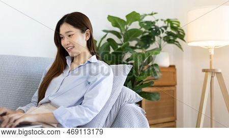 Woman using laptop to work or do homework at home with smiling face in her living room, Creating hap