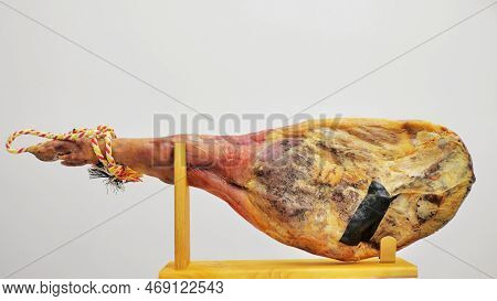 A Front Leg Of Serrano Ham Mapped On A Wooden Stand On A White Background.