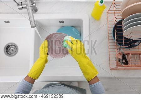 Woman Washing Plate Above Sink In Modern Kitchen, Top View