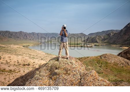 Professional Photographer Takes Photos With Camera In Hands On Rocky Peak. Look At Camera, Cipy Spac