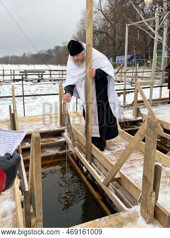 Moscow, Russia - January 18, 2023: The Priest Dunks The Cross Into The Water For The Rite Of Baptism