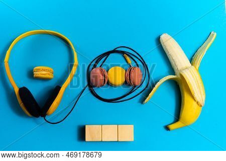 Minimalism Flat Lay Concept, Listens To Music. Headphones, Banana On Blue Background. Top View