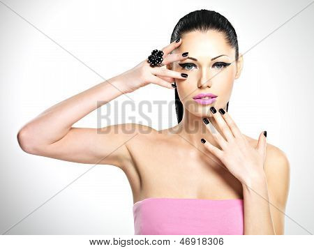 Volto di donna bella con unghie nere e labbra rosa