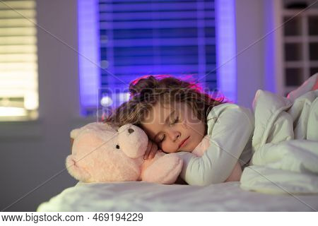 Bedding Child. Lovely Face Of Blonde Caucasian Kid Boy, Sleeping With A Toy Teddy Bear On Bed. Sweet
