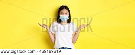 Covid-19, Quarantine And Social Distancing Concept. Confused Asian Woman In Medical Mask Shrugging S