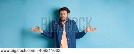 Confused Young Man With Beard, Shrugging Shoulders And Looking Clueless At Camera, Know Nothing, Sta