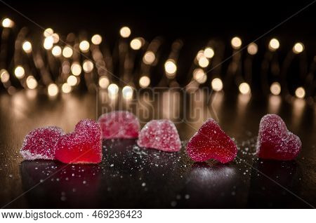 Six Red Sugar Marmalade Candies In Shape Of Heart On Black Background, Lit From Side, Behind Round Y