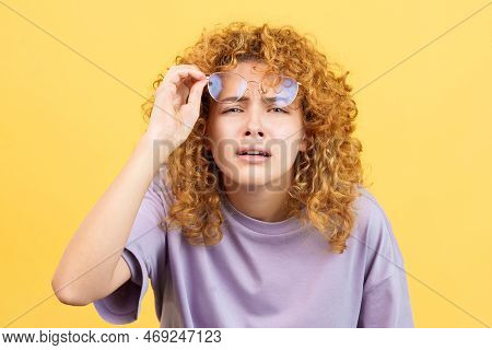 Young Woman Taking Off Her Glasses To See Far Away