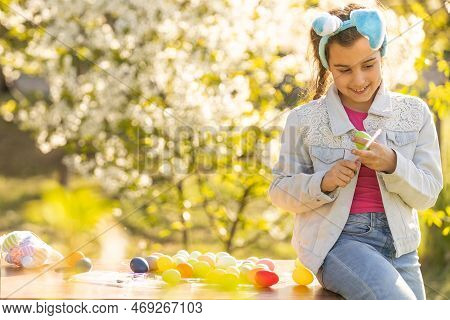 Teenage Girl Paints Easter Eggs In The Garden.
