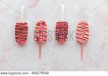 Alternating Up And Down Facing Valentine Cakesicles On A Pink Marble Surface.