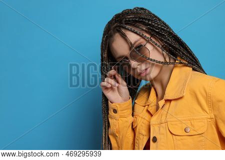 Beautiful Woman With Long African Braids And Sunglasses On Blue Background, Space For Text