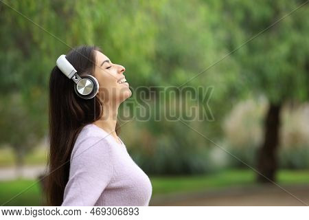 Side View Portrait Of A Happy Woman Breathing Listening Audio Guide In A Park