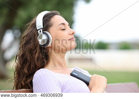 Relaxed Woman Resting In A Bench Listening Music