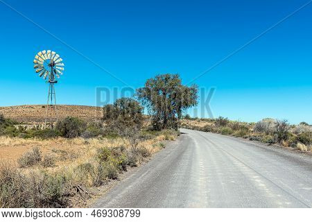 A Landscape, With A Corrugated Gravel Road, Windmill, Dam And Trees, Between Loxton And Fraserburg I
