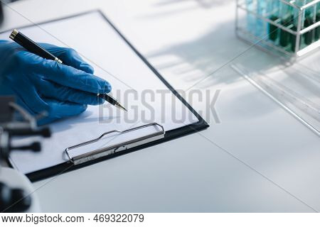 Lab Assistant, A Medical Scientist, A Chemistry Researcher Holds A Glass Tube Through The Blood Samp